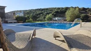 una piscina con vista sul verde della campagna gallurese e alcune sdraio in primo piano